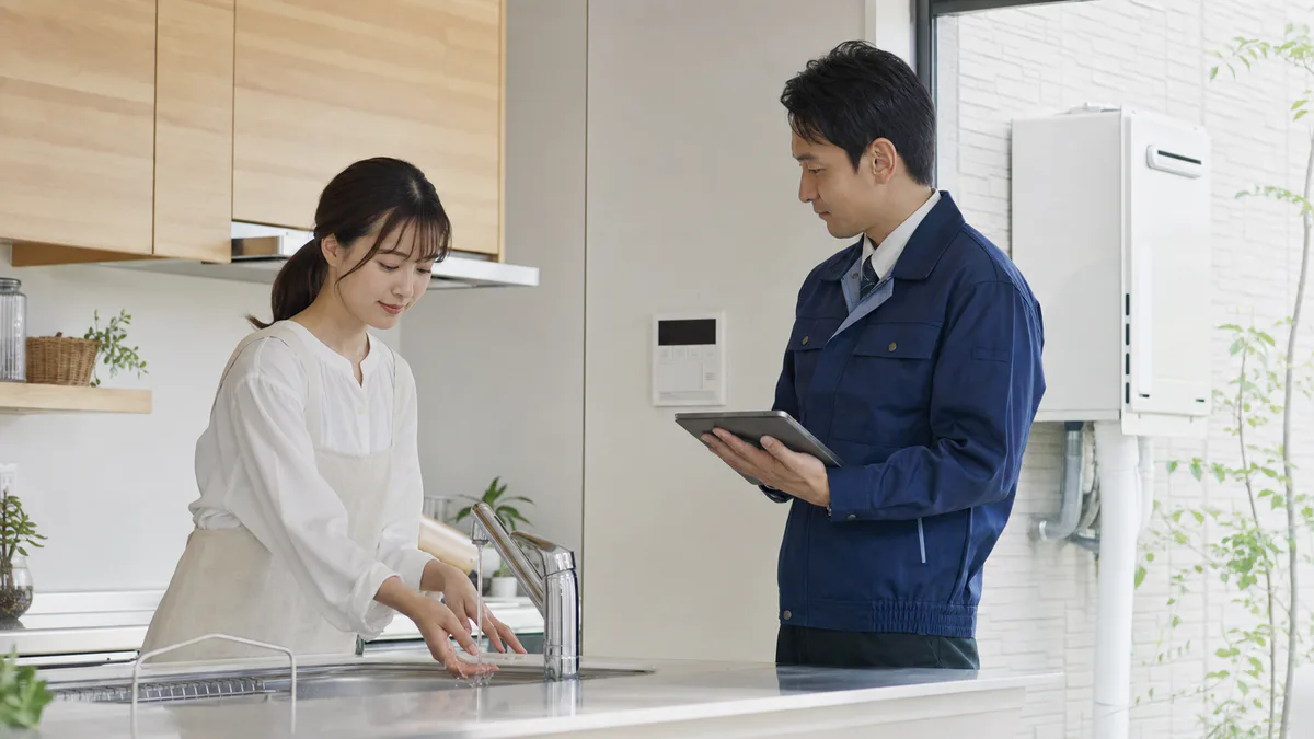 お湯が出ない蛇口と給湯器の状態を専門スタッフへ相談する様子